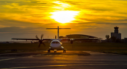 Fototapeta na wymiar Śmigła samolot kołowania wokół lotniska na zachodzie słońca