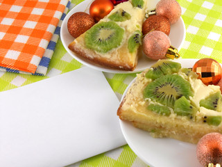 kiwi cake on plate with white blank paper and christmas balls