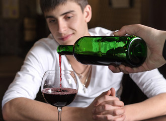 Barman or waiter pouring red wine