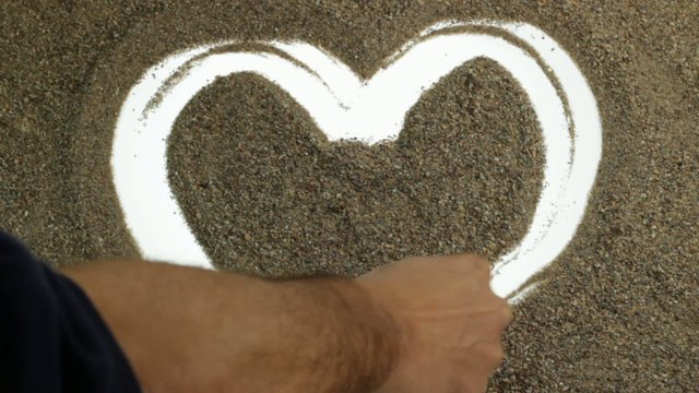 heart symbol backlit finger painting on sand