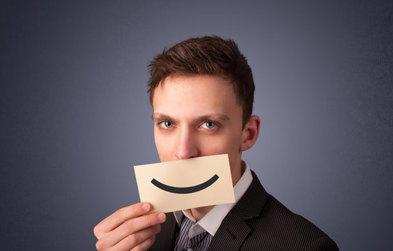 Happy businessman holding funny white card on his mouth