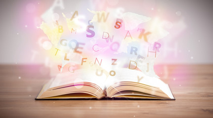 Open book with glowing letters on concrete background