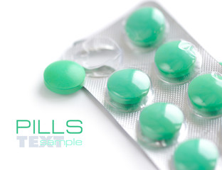 Green pills and blisters on white background
