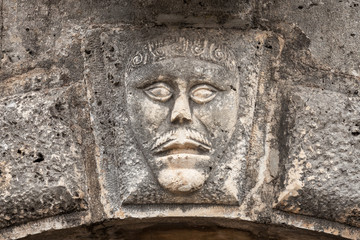Fototapeta na wymiar Bas-relief with man's face on ancient house facade in Perast