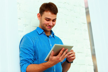 Young happy businessman standing with tablet 