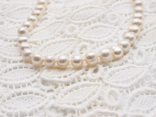 Obraz premium White pearl necklace on white lace background