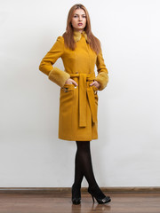 Sexy elegant woman wearing classic yellow coat with belt