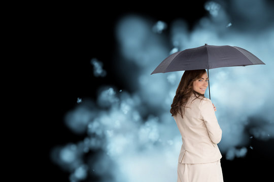 Composite image of rear view of classy businesswoman holding umb