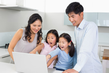 Shocked family of four using laptop in kitchen