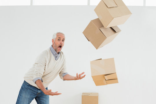 Side view of a mature man with falling boxes