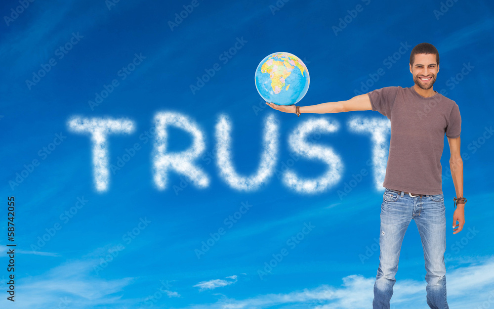 Fototapete Composite image of handsome man holding out a globe