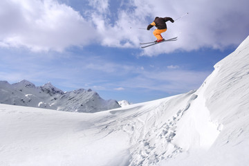 Jumping skier at jump in high mountains at sunny day