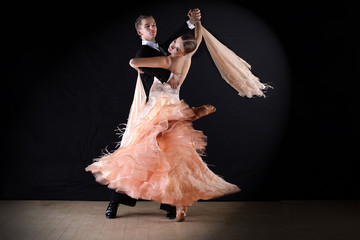 Latino dancers in ballroom against on black