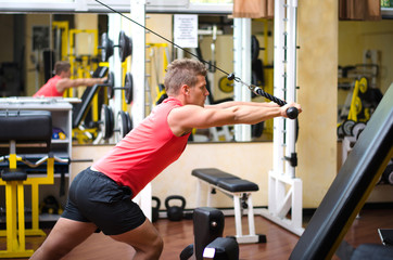 Fototapeta premium Young man training on gym equipment