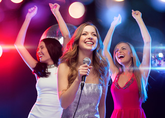 three smiling women dancing and singing karaoke