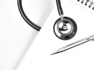 Stethoscope and silver pen on meadical notebook