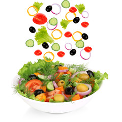 Fresh mixed vegetables falling into bowl of salad isolated