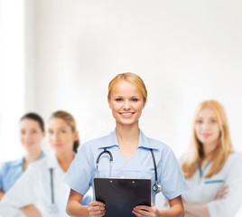 smiling female doctor or nurse with clipboard