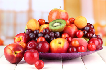 Assortment of juicy fruits on wooden table, on bright