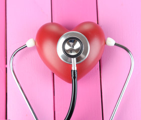 Stethoscope and heart on wooden table close-up