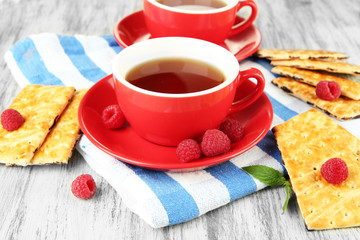 Cups of tea with cookies and raspberries on table close-up