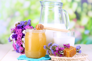 Honey and milk on wooden table on natural background