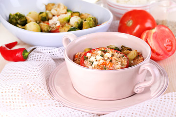 Stuffed tomatoes in pan and bowl on wooden table close-up