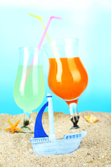 Beach cocktails in sand on blue background