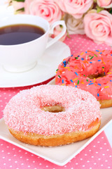 Sweet donuts with cup of tea on table close-up