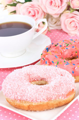 Sweet donuts with cup of tea on table close-up