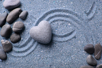 Fototapeta na wymiar Szary Zen kamień w kształcie serca, na tle piasku