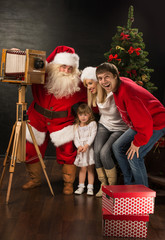 Santa Claus taking picture of full family with old wooden camera
