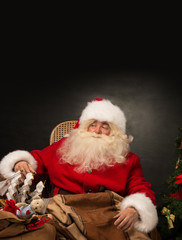 Santa Claus with a huge bag full of Christmas presents sitting i