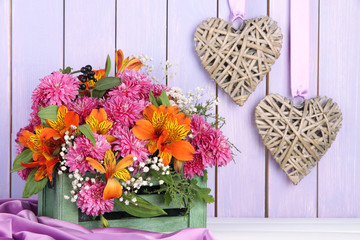Flowers composition in crate with decorative hearts