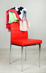Heap of  clothes on color chair,  on gray background