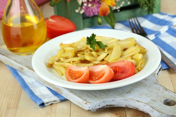 Ruddy fried potatoes on plate on wooden table close-up