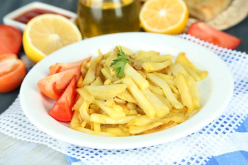 Ruddy fried potatoes on plate on wooden table close-up