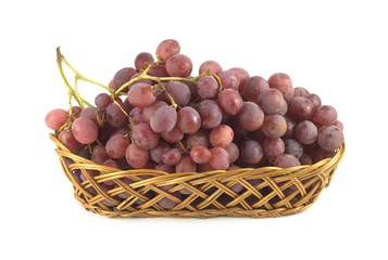 Red grape branch in long wicker basket front view isolated
