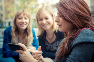 three friends woman at the bar using phone