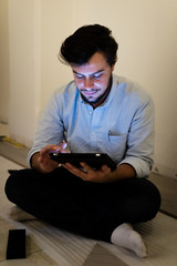 young man using and illuminated by the light of tablet