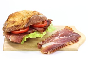 Holzbrettchen mit Schinkenbrötchen isoliert auf weißem Hintergrund