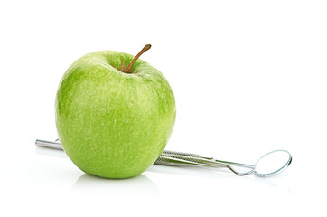 Green apple and dental tools isolated on white