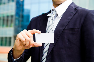 young businessman holding visit card in hand and standing in the