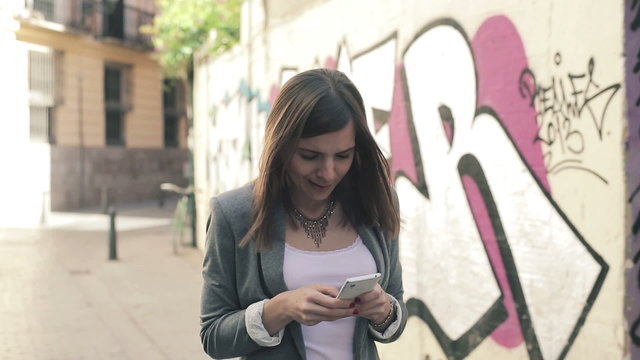 Elegant woman texting on smartphone in the city, steadicam shot