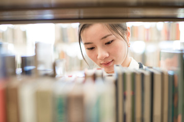 Woman looking for book from bookshelf