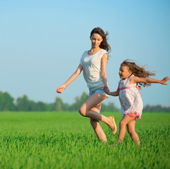 Young happy girls running at green wheat field