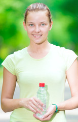 Woman drinking cold mineral water from a bottle after fitness ex