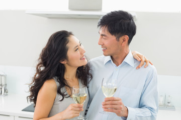 Loving young couple with wine glasses in kitchen