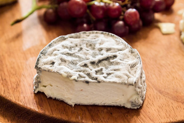 cheese on wooden plate with grapes