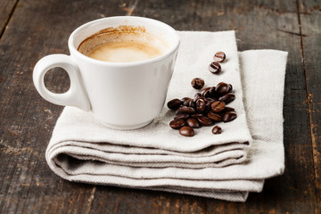 Coffee cup with coffee beans on wooden background
